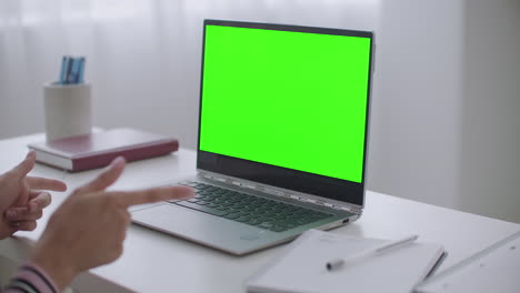 woman-is-communicating-online-by-video-chat-on-laptop-with-green-screen-for-chroma-key-technology-closeup-view-on-table